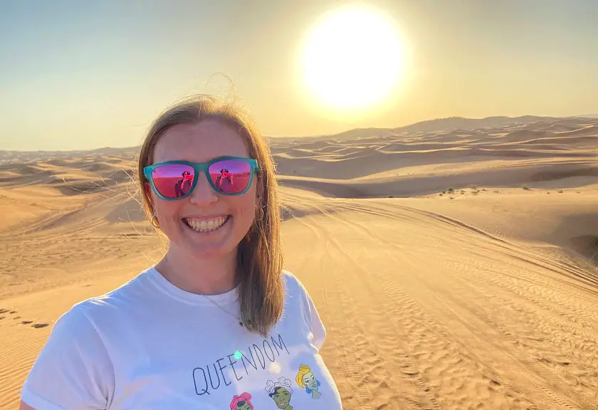 Mel smiling in the Dubai desert wearing a white tshirt