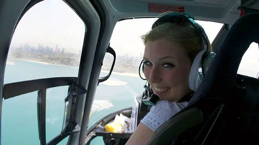 Mel smiling looking back from the front seat of a helicopter going over Palm Island in Dubai UAE