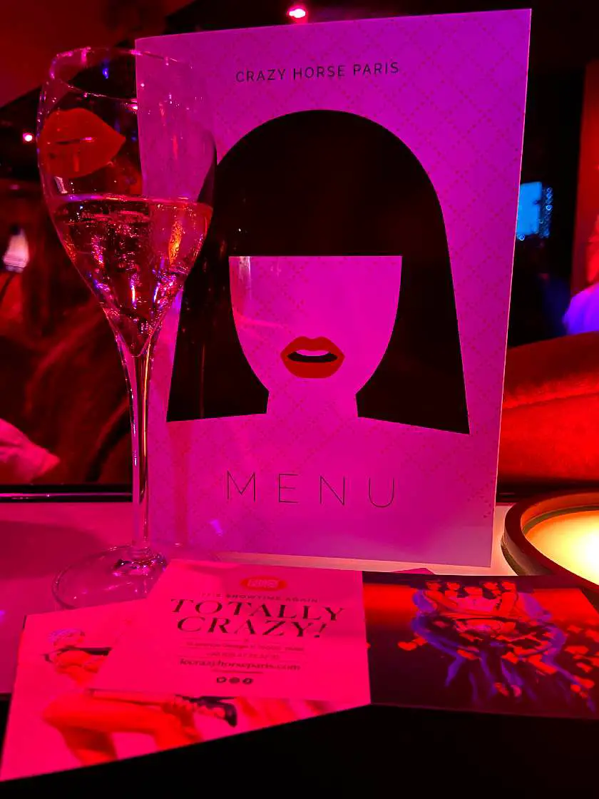 Menu and glass of champagne at the Crazy Horse Paris with pink light shining on it