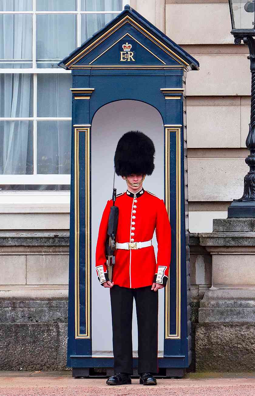 Beef eater guard holding a weapon stood by a blue guarding box in London