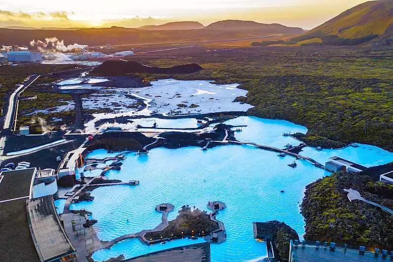 Aerial view of the large Blue Lagoon complex at sunset with mountain peaks in the background