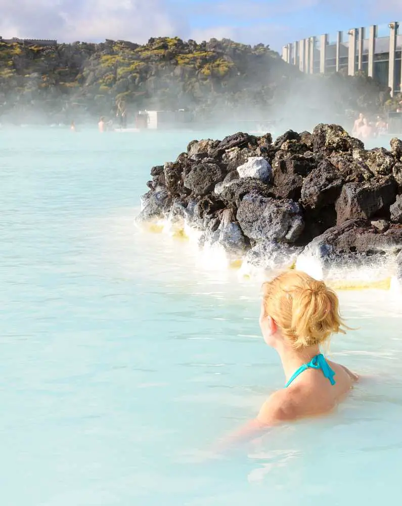 Blonde-haired woman with her back to the camera alone in the Blue Lagoon 