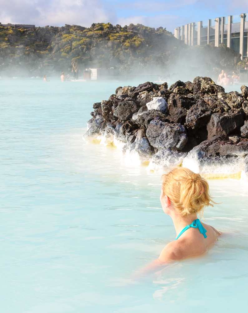 Blonde-haired woman with her back to the camera alone in the Blue Lagoon 