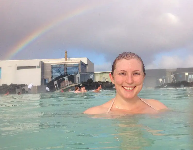 Mel smiling in front of a rainbow in the water at the Blue Lagoon