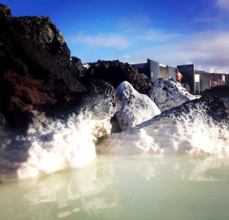 Black rocks up close with white mineral residue at the bottom of them from the Blue Lagoon