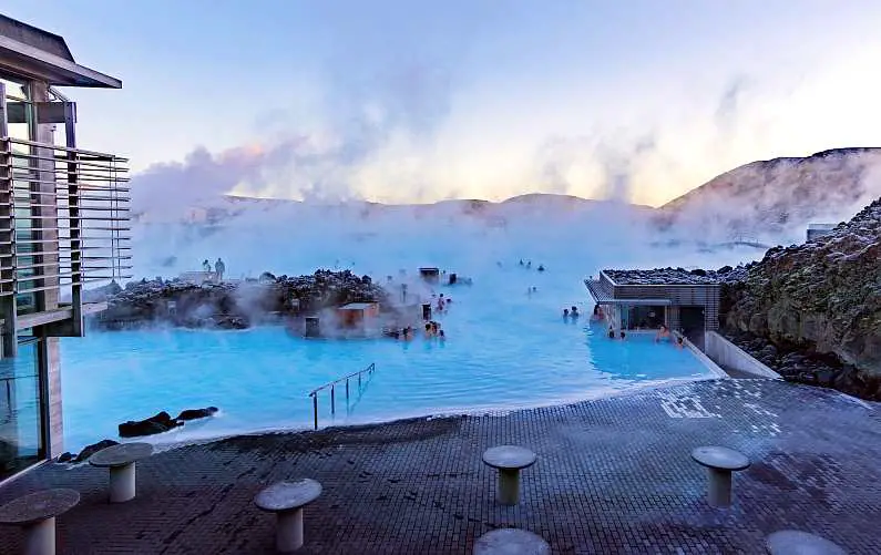 People swimming in the Blue Lagoon complex covered in white smoke coming from the water
