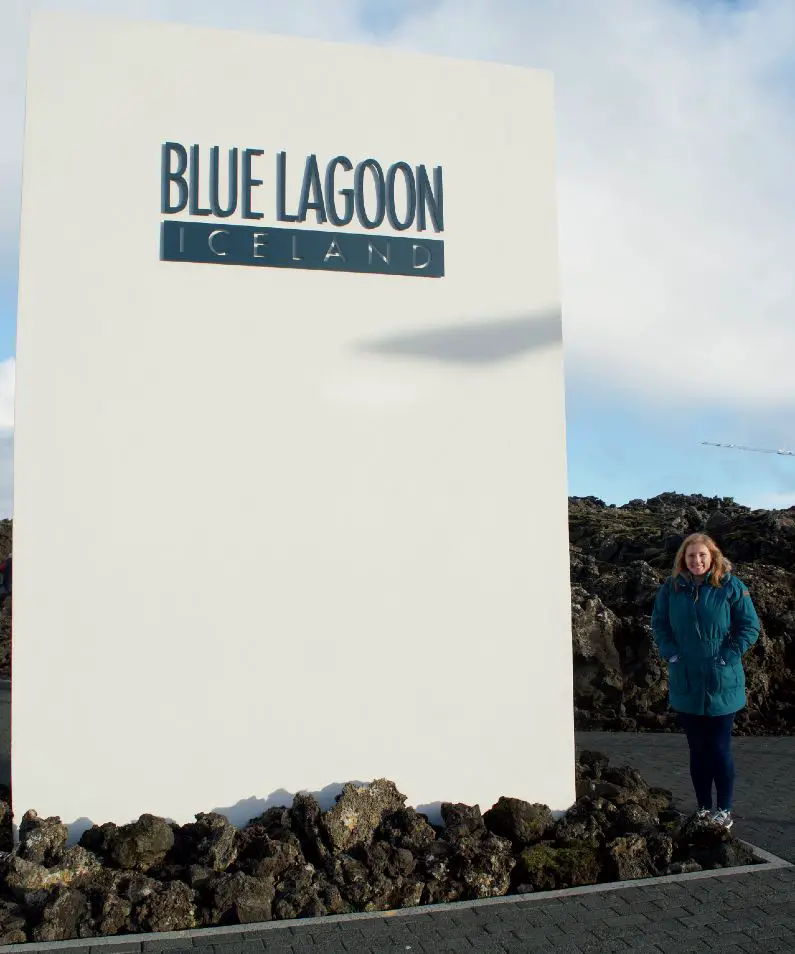 Mel stood next to the Blue Lagoon sign outside with her hands in her pockets wearing a turquoise coat, jeans and converse 