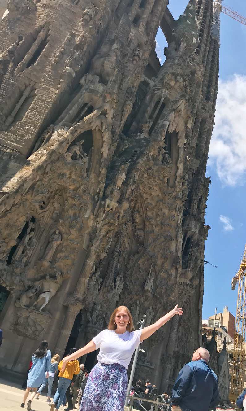 Mel with her arms extended outside the entrance to Sagrada Familia