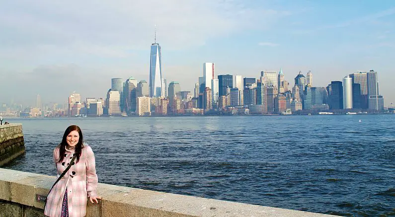 Mel standing in front of the New York skyline from Liberty Island