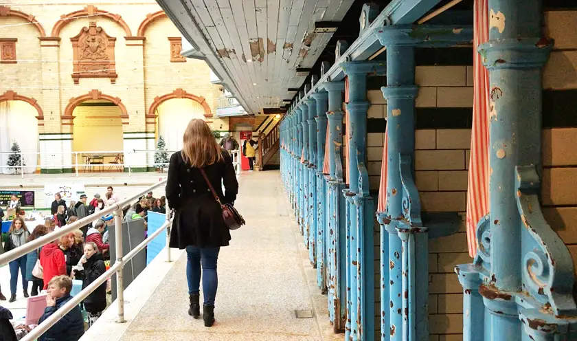 Mel walking by swimming pool, Edwardian changing rooms, inside Victoria baths, guide to Manchester's vegan Christmas Festival