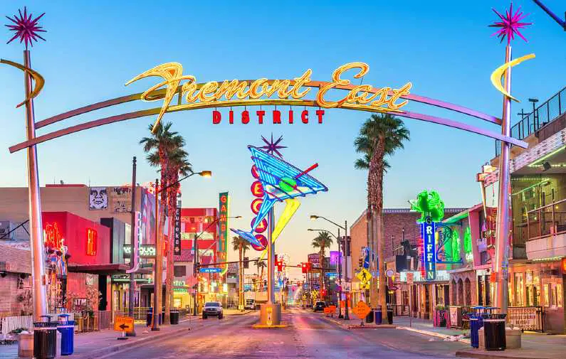 Front of Fremont East District sign with lit up neon signs on both sides of the street including a martini glass in the middle of the road