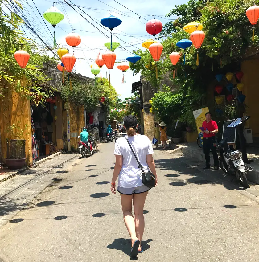 Mel from Footsteps on the Globe walking down a street in Hoi An Vietnam with colourful lanterns hanging above her head from one side of the street to the other, Breaking up, backpacking and beginning again