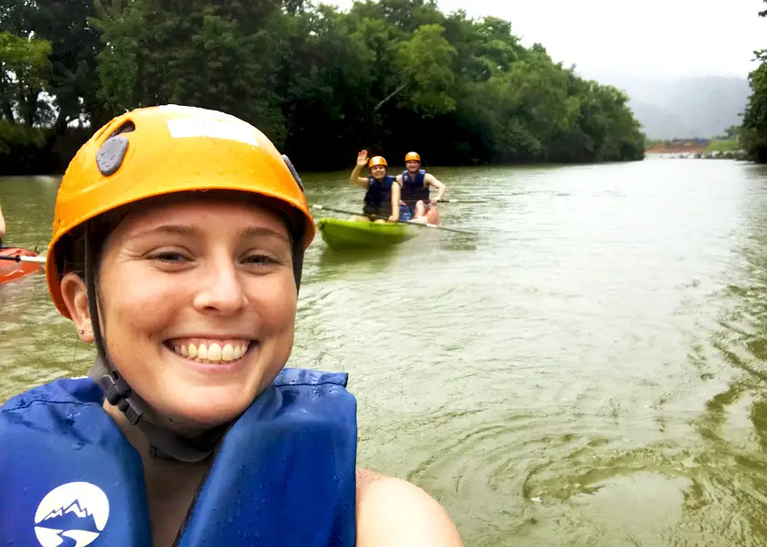 Mel from Footsteps on the Globe in a lifevest and yellow helmet taking a selfie whilst kayaking down the Nam Song River in Laos, Breaking up, backpacking and beginning again