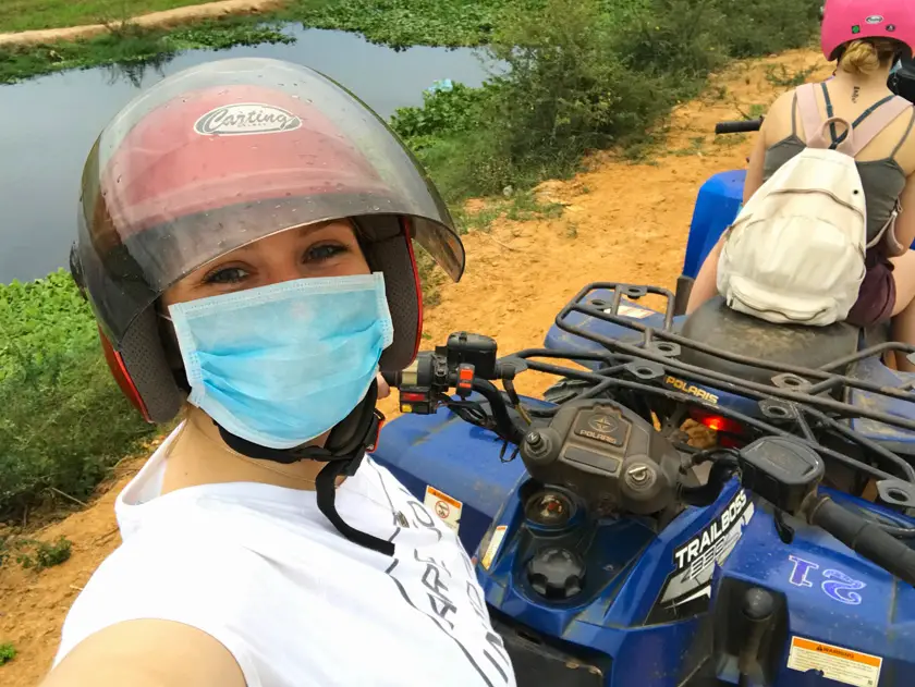 Mel from Footsteps on the Globe quad biking in Cambodia taking a selfie wearing a red helmet and face mask in Siem Reap in Cambodia, Breaking up, backpacking and beginning again
