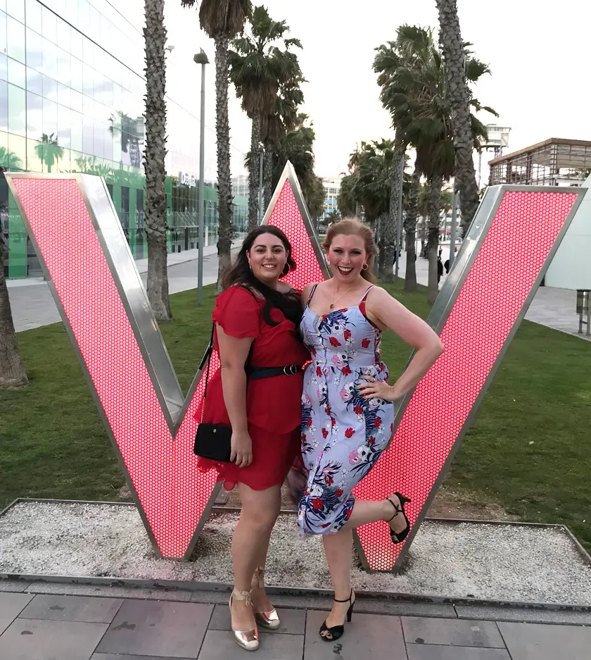 Mel from Footsteps on the Globe dressed up to go out for the night with her friend Kate in front of the W Hotel's 'W' sign in Barcelona Spain, Breaking up, backpacking and beginning again