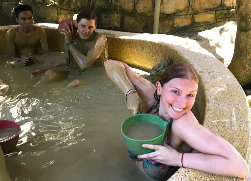 Mel from Footsteps on the Globe holding a bucket of mud in a mud bath at a Mud Spa in Nha Trang in Vietnam