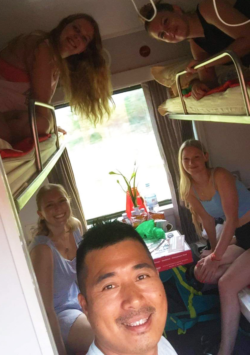 Mel from Footsteps on the Globe with friends each sat on a bunk on an overnight train in Vietnam taken selfie style from the door to the room