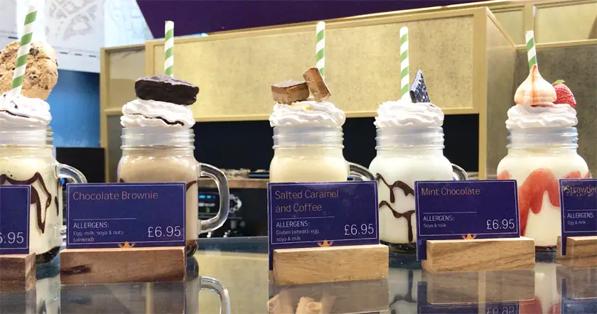 Row of five different non-vegan milkshakes on the counter at The Chocolate Frog Cafe 