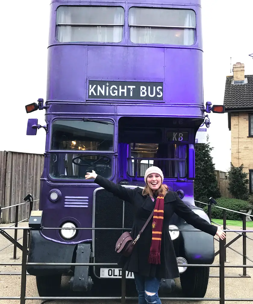 Mel from Footsteps on the Globe with her arms outstretched in front of the purple Knight Bus on the backlot of The Harry Potter Studios London