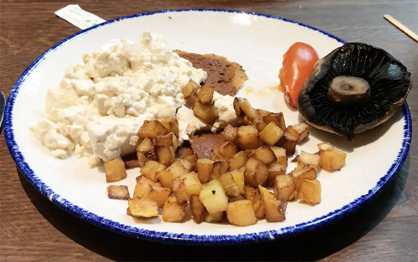 Vegan breakfast at The Food Hall with vegan bacon, tofu scrambled eggs, tomato, mushroom and diced fried potatoes