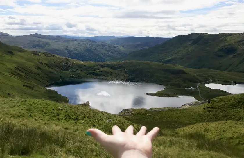Mel holding out her hand to showcase the beautiful Lake and hills at Snowdon National Park.