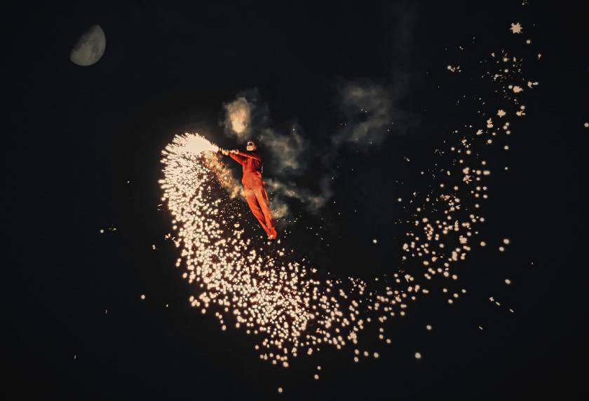 Derry Halloween Festival with a man dressed as a day of the dead ghoul flying in the air with a sparkler in the dark