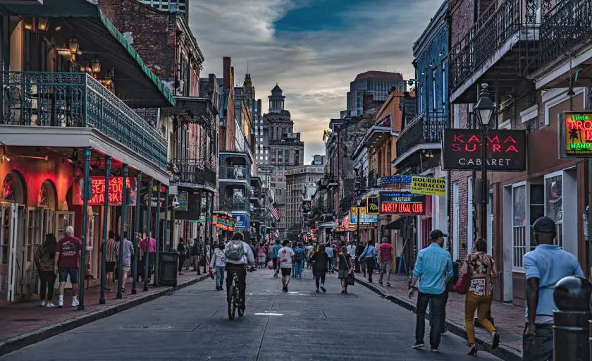 Main tourist street in New Orleans (Bourbon Street) at dusk with people strolling and street signs lit up