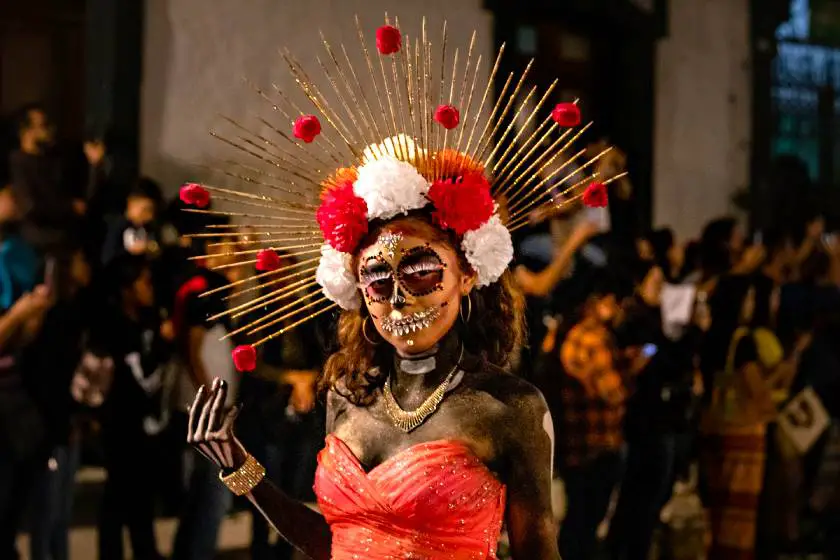 Woman dressed in a red Day of the Dead outfit with face paint and head dress in Oaxaca, Mexico