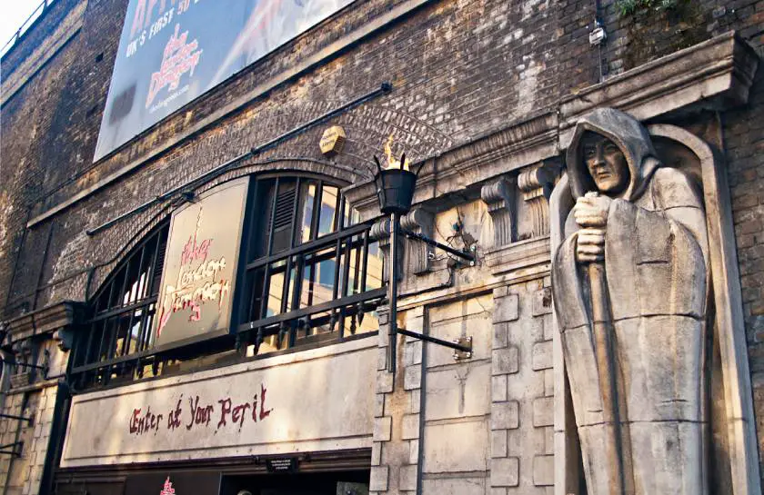 Outside of London Dungeon with formidable stone statue and black railings