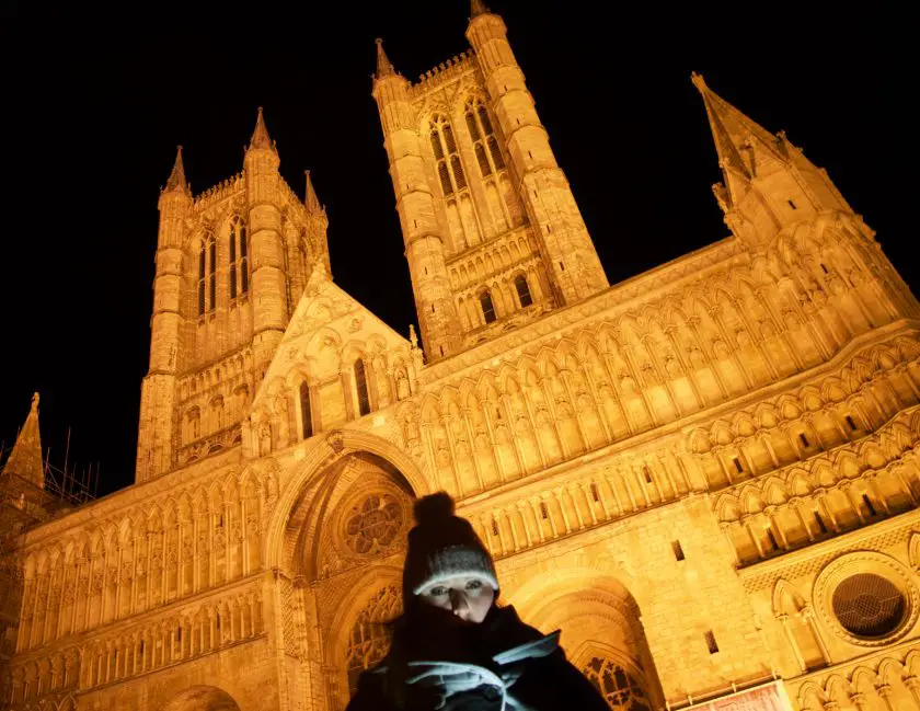 Lincoln Cathedral lit up at night on the Lincoln ghost walk with Mel in the foreground under a shadow