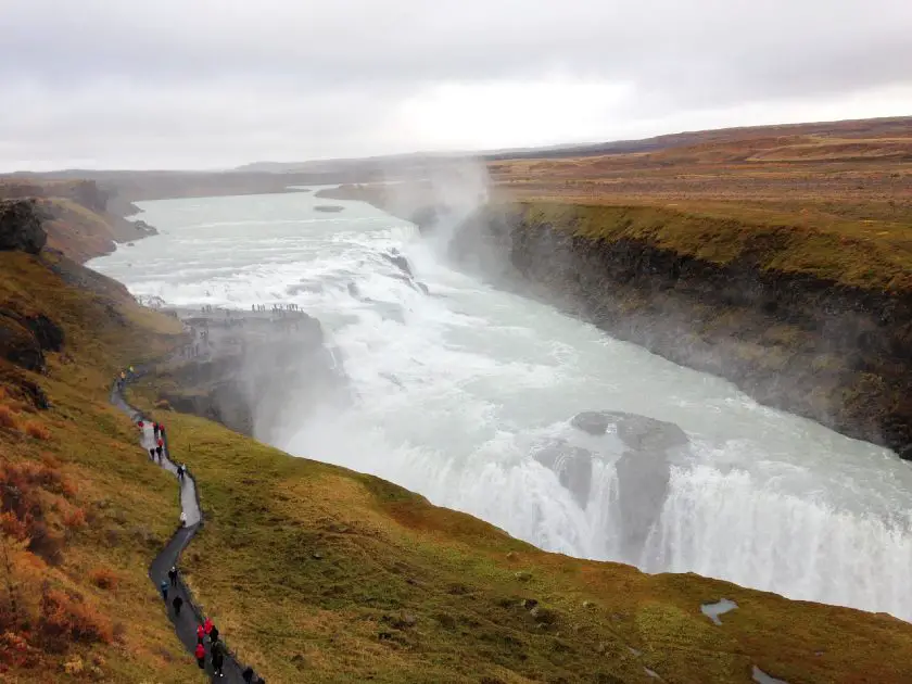 People walking down a path towards the top of Gullfoss Falls in Iceland