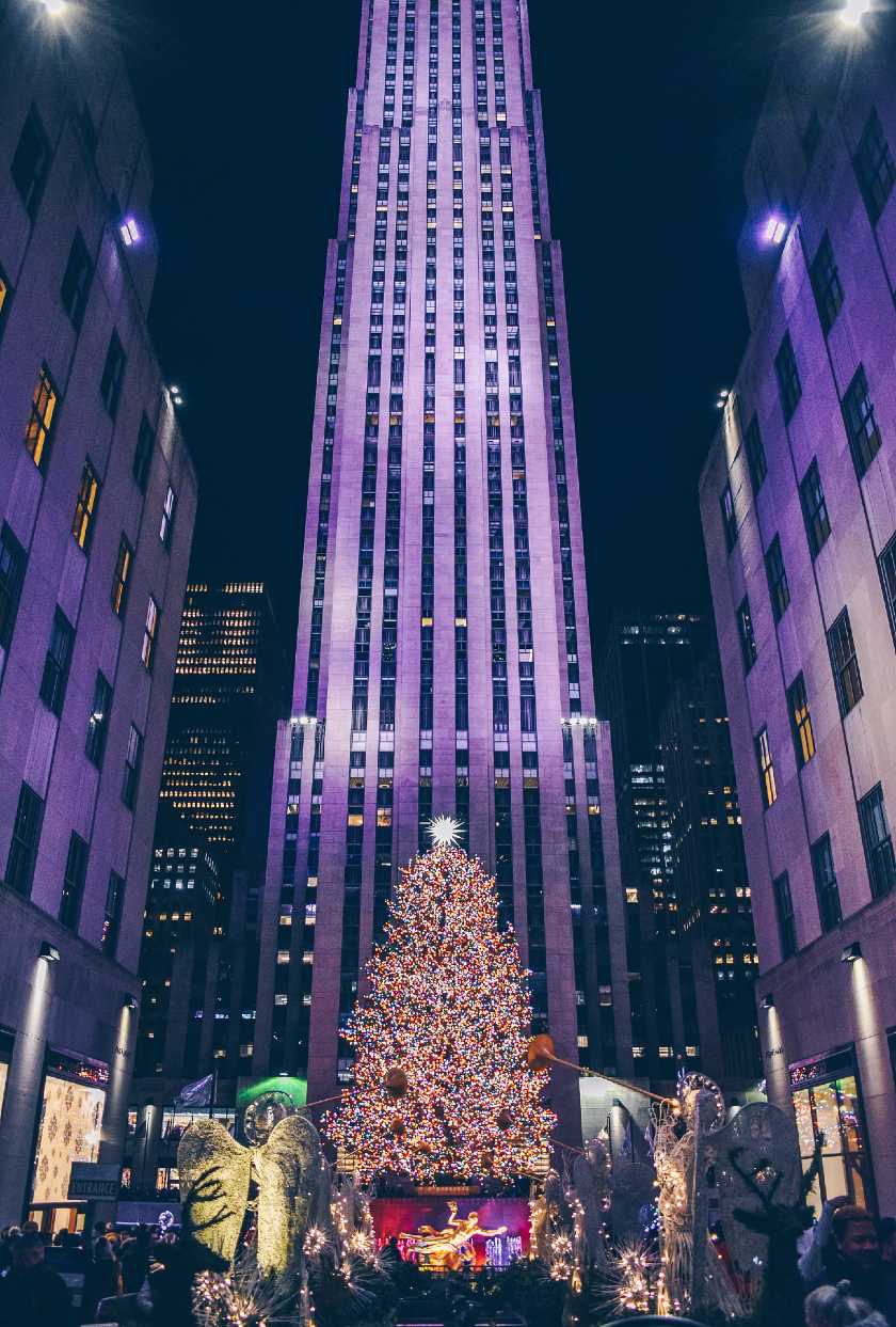 Christmas tree and decorations at Rockefeller Center in New York with tall skyscrapers surrounding them