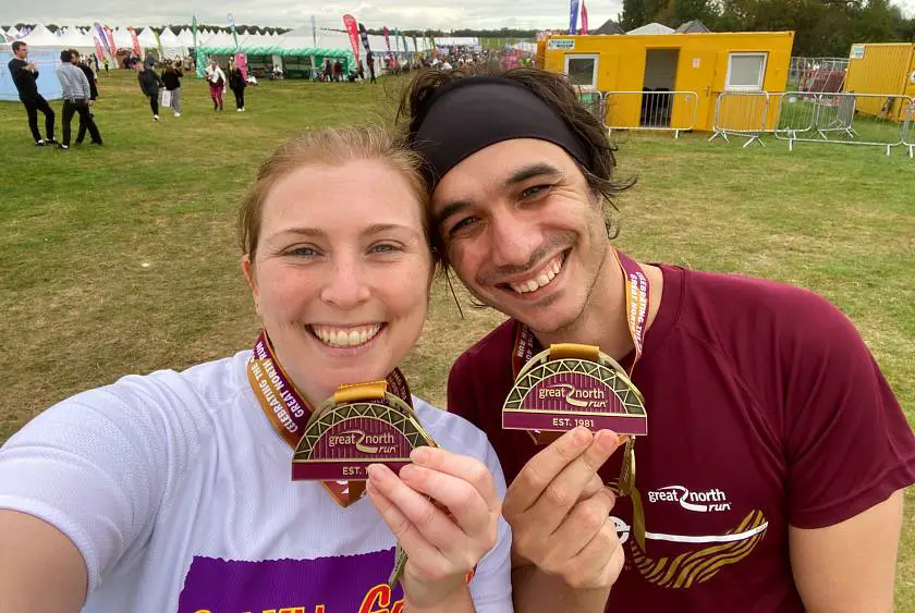 Mel and her boyfriend after the Great North Run holding up their medals and smiling