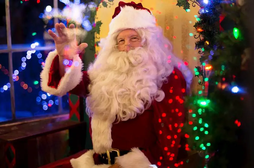 Santa waving sat down in his grotto