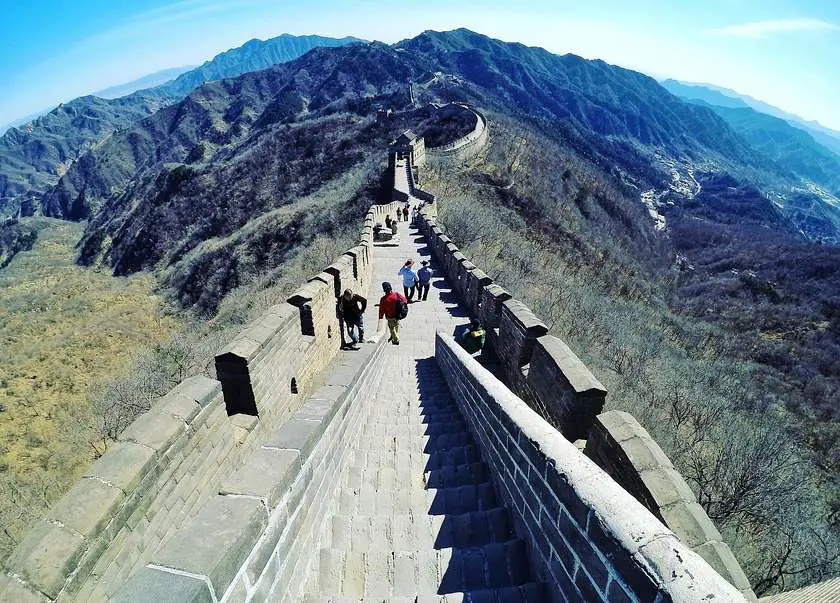 People walking on the Great Wall of China with mountains in the background