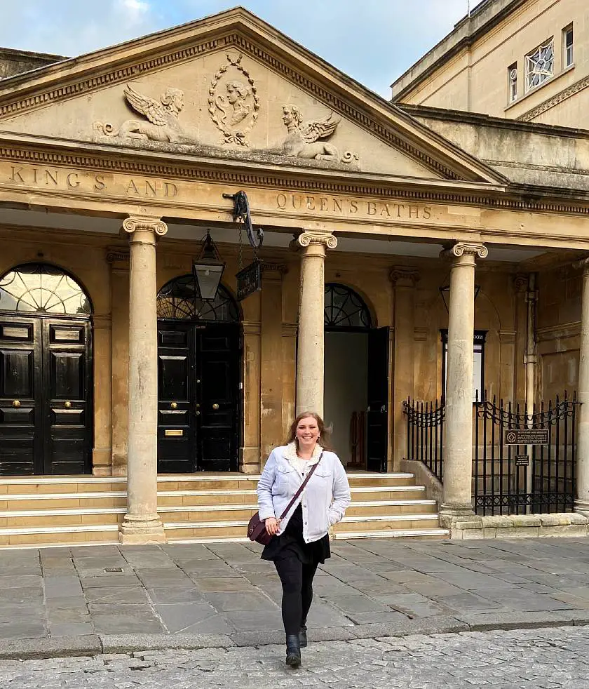 Mel walking in front of the pump house columned entrance of the Roman Baths in Bath 