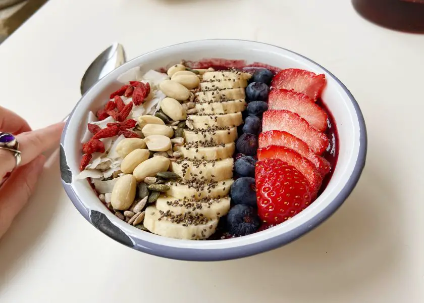 Vegan smoothie bowl with banana, blueberry, strawberry, cashew nuts, goji berries and coconut flakes
