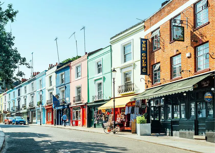 Row of candy coloured houses with shops underneath on Portobello Road in London 