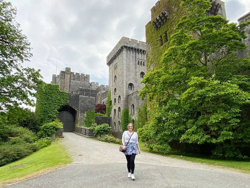 Mel walking in front of Penrhyn Castle covered in greenery