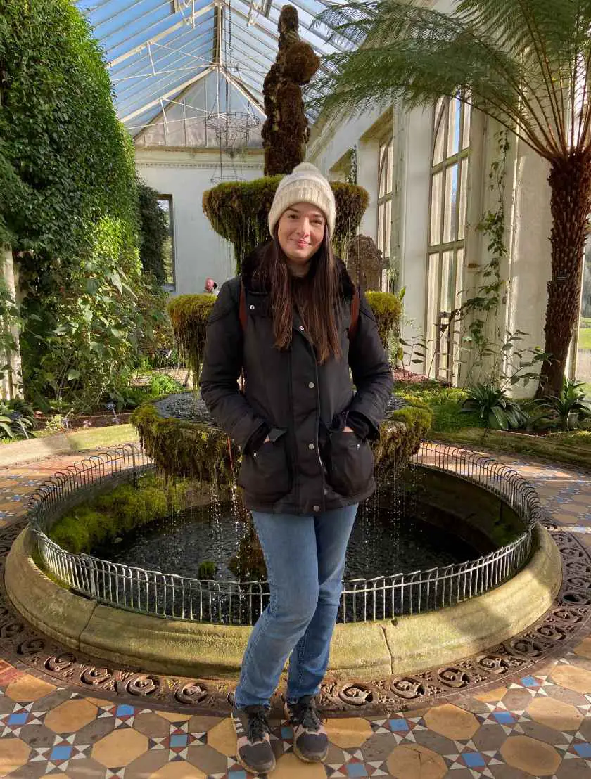 Becky in front of a moss covered water fountain in Lyme Park's victorian greenhouse