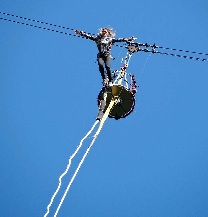Girl bungee jumping from a platform against a blue sky