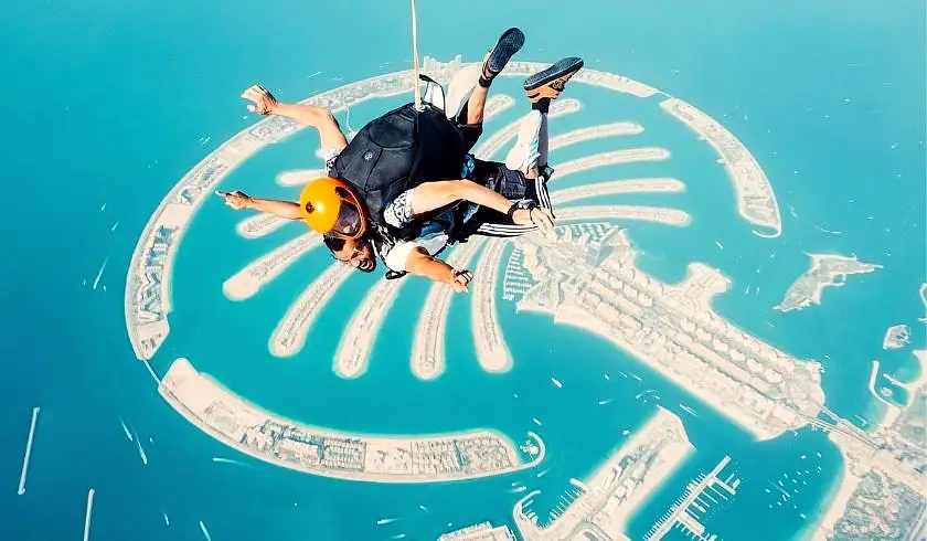 Man tandem skydiving over palm island in Dubai