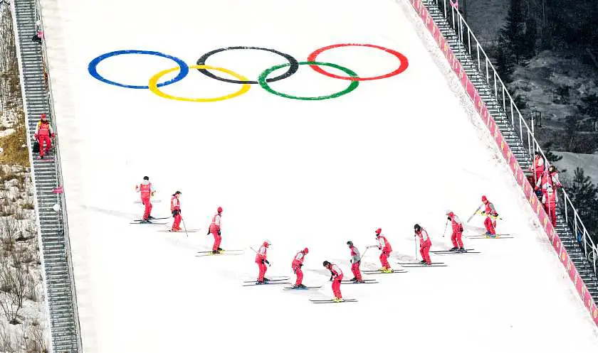 Skiers with the olympics symbol in the background