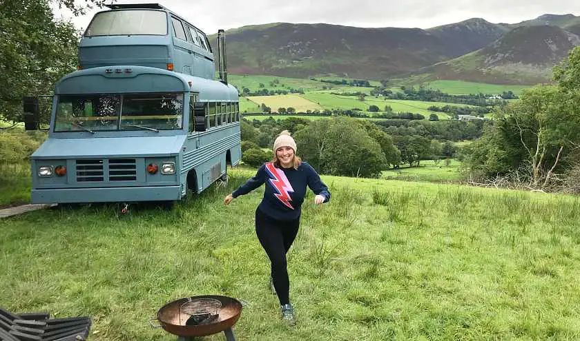 Mel in a green field with a blue bus in the background