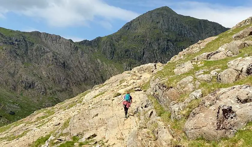 Mel scrambling over beige rocks in the final ascent before Snowdon on the Pyg Track