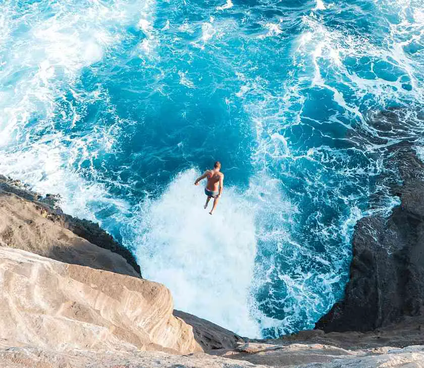 Man cliff jumping into a rough sea in Hawaii 