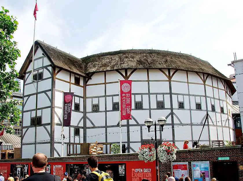 Outside Shakespeare's Globe Theatre in London, a white circular Elizabethan style building made with a thatched roof and timber beams