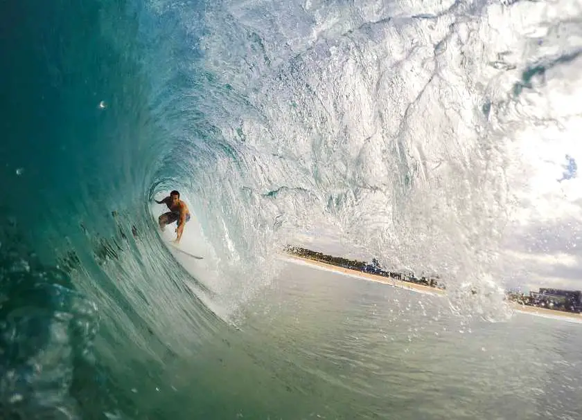 View of a surfer riding a curved wave taken from under the wave