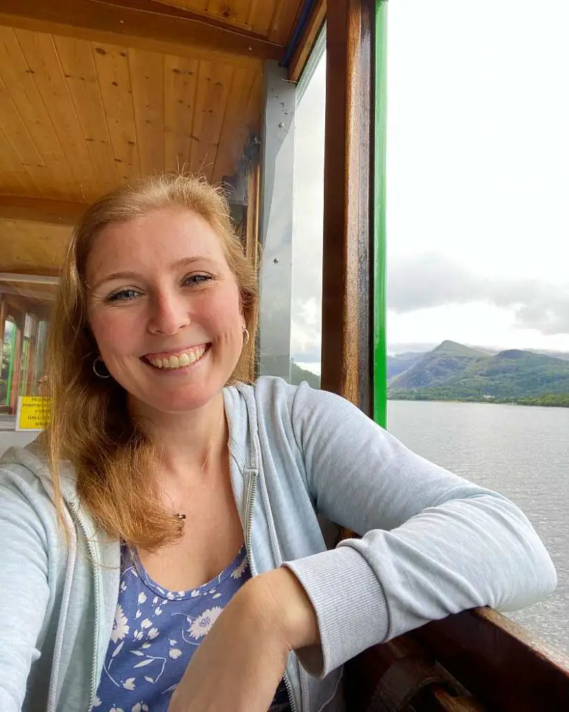 Mel looking out from a green steam train window pinterest image with mountains and Lake Padarn in the background