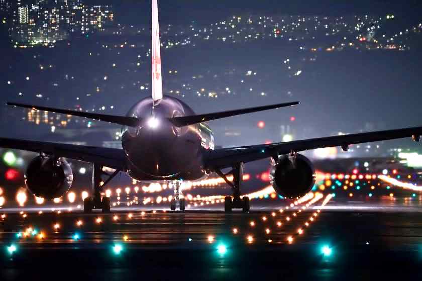 Plane taking off on a lit runway at night